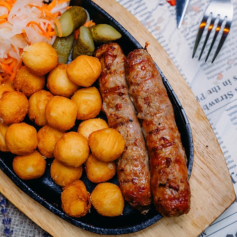 Свиные колбаски с картофельными шариками и соленьями
